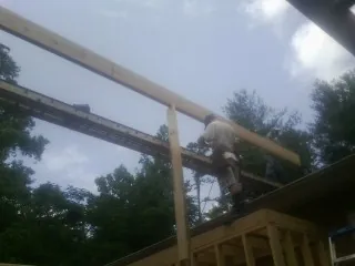 Carpenter setting a ridge beam over a new addition frame — Ice Dam Removal by Roofing Brothers in New York Mills