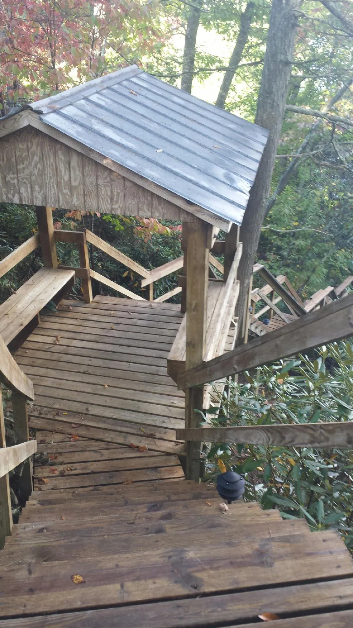 Metal roofed shelter over wooden steps on a wooded walkway — Skylight Repair & Installation work by our crew in New York Mills